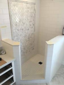 This image features a walk-in shower made of white tile. 