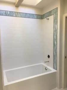 A bathtub featuring white tile as well as light blue tile that accents around the exterior. 