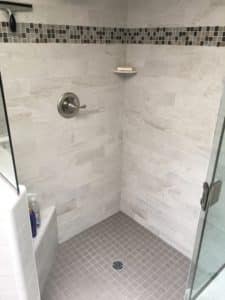 This image features a walk-in shower with grey tile. 